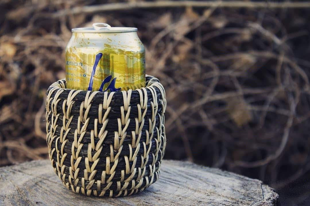 Coiled basket around a soda can. The scotchbroom is dark green and the stiching is light beige.